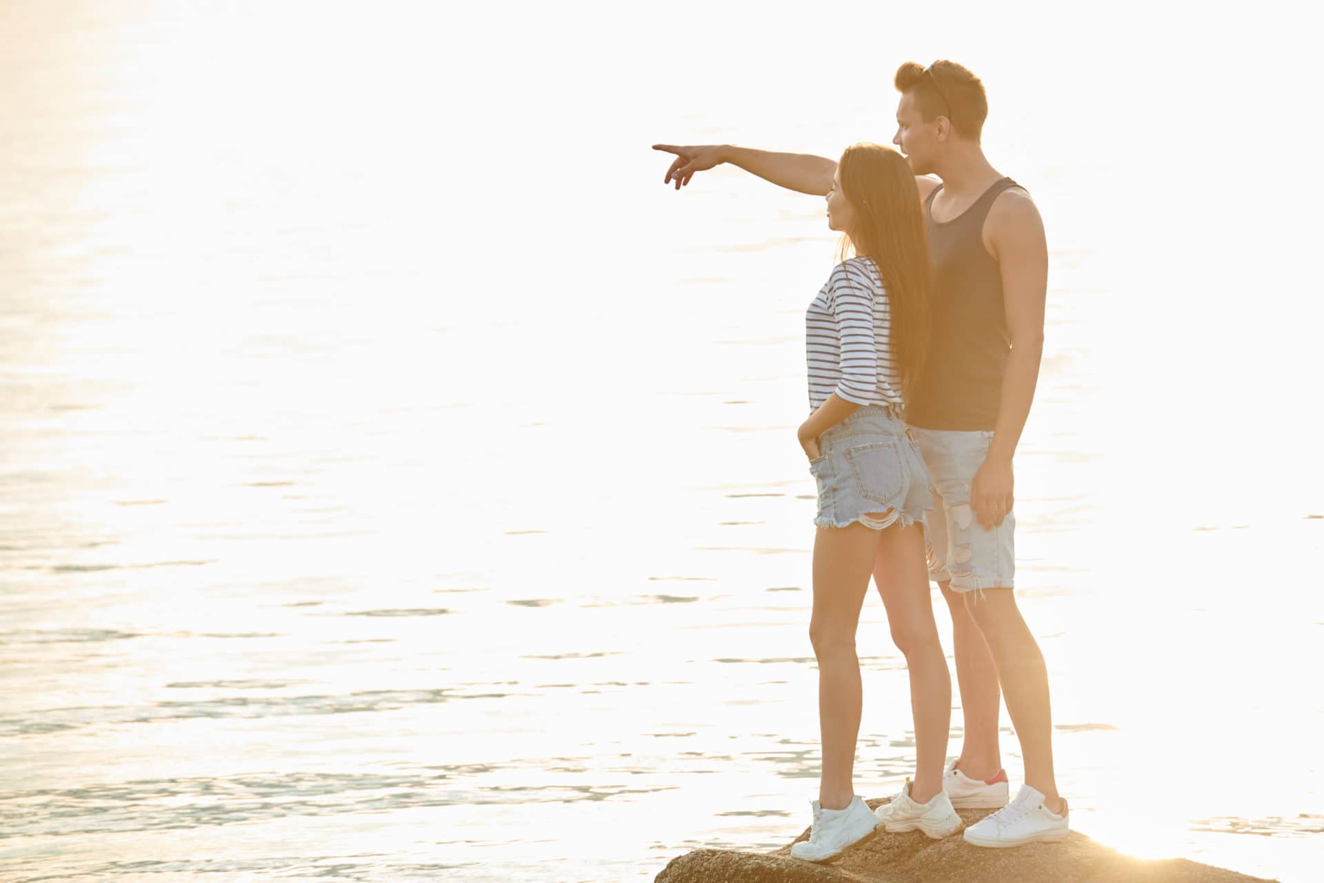 Couple on the summer vacation Romantic young couple standing on the rock and looking at horizon together